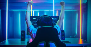 Young person sitting in gaming chair in front of computer with head phones on