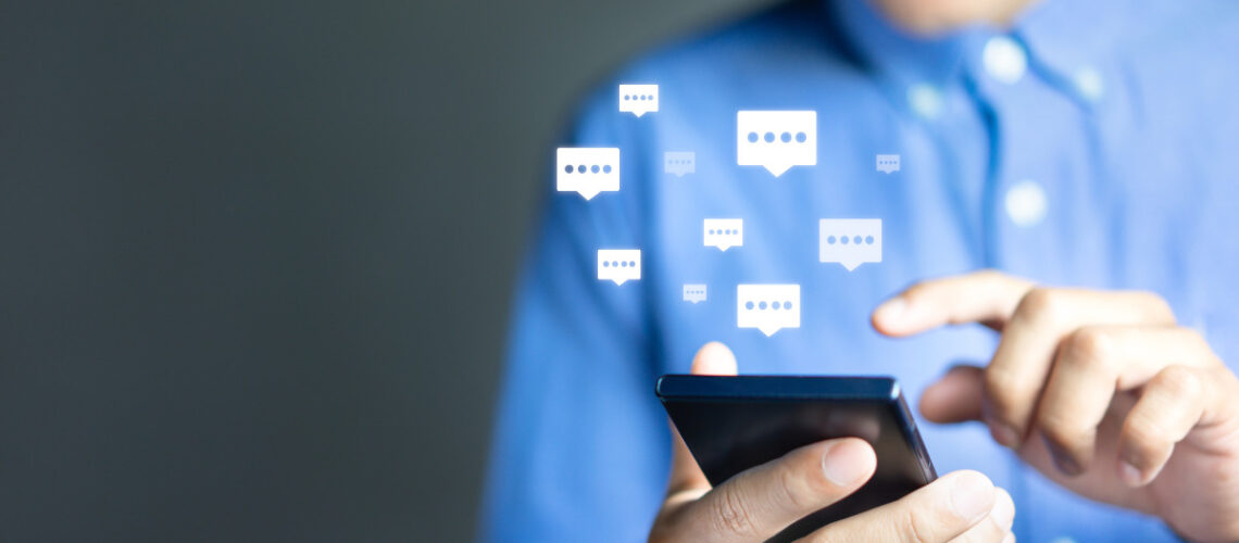 Individual in a blue shirt sending online messages to a chatbot.