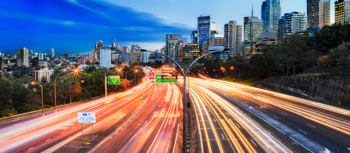 Blurred image of a freeway at night outside of a city.