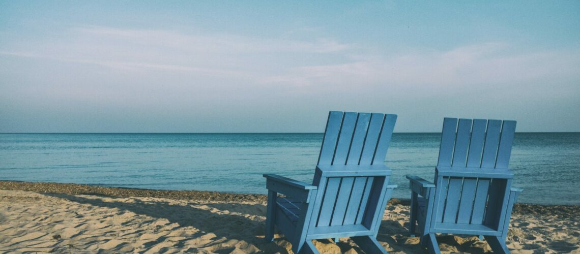 two blue beach chairs near body of water